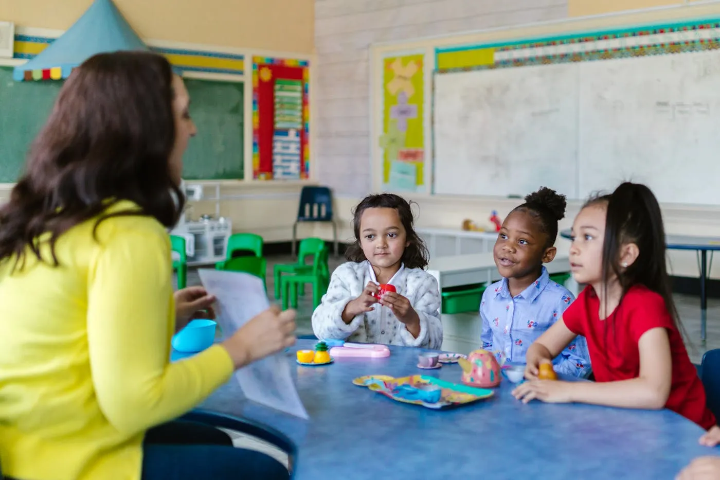 A teacher working with young students at a table