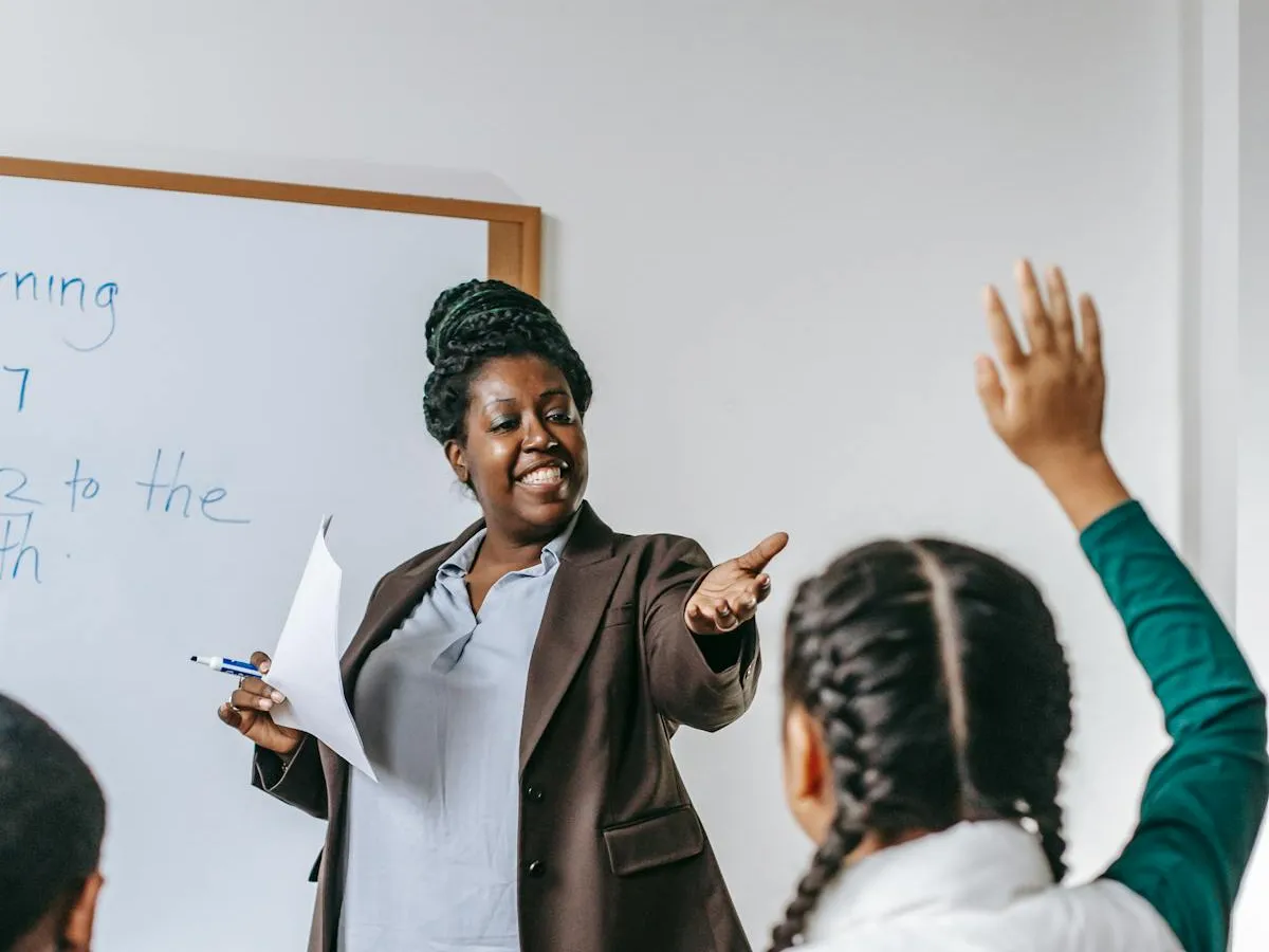 A smiling teacher welcoming questions from her class