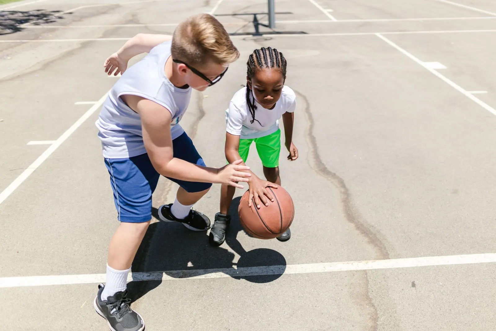 Two kids working on dribbling drills on an outdoor court