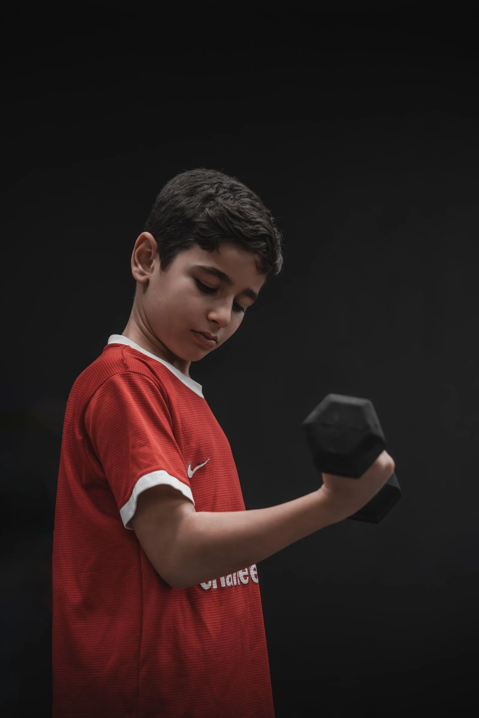 A young athlete focused on a dumbbell curl during strength training